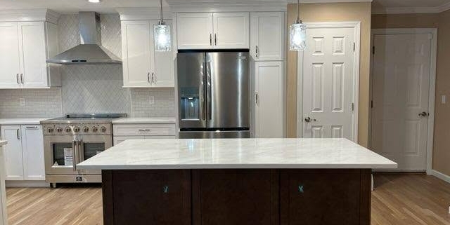 Modern renovated kitchen featuring a dark wood island with white marble countertop, stainless steel appliances, and white cabinetry in a Suffolk County home addition.