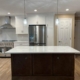 Modern renovated kitchen featuring a dark wood island with white marble countertop, stainless steel appliances, and white cabinetry in a Suffolk County home addition.