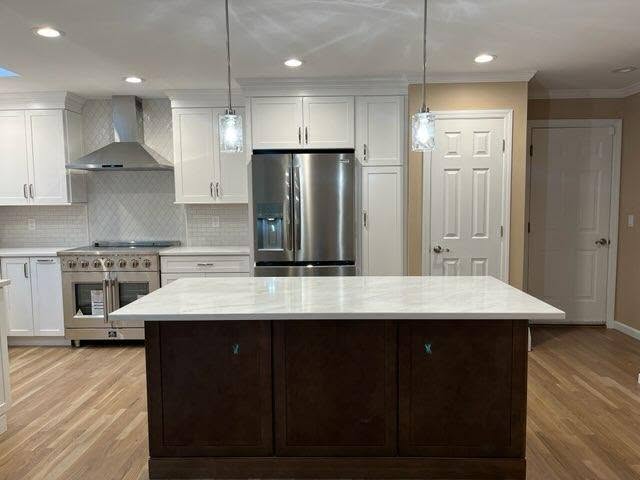 Modern renovated kitchen featuring a dark wood island with white marble countertop, stainless steel appliances, and white cabinetry in a Suffolk County home addition.