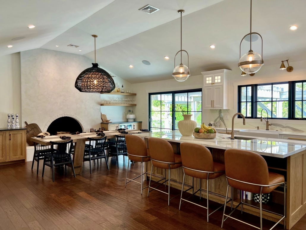 Is it Better to Build Up or Out for a Home Addition in Suffolk County Open-concept kitchen and dining area in Suffolk County with vaulted ceiling, large island, leather counter stools and arched fireplace